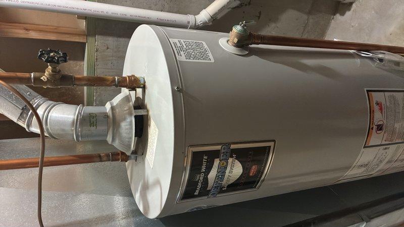 Conducted on-site assessment of residential water heater in basement utility area for replacement estimate. Unit evaluated is over 10 years old, showing visible signs of age including oxidation on copper supply lines and connections. Documented existing installation configuration including top-mounted copper piping with shut-off valves, pressure relief valve, expansion tank, and current venting system. Photographed unit specifications, mechanical room layout, and all plumbing connections to provide accurate replacement proposal for standard residential water heater installation.