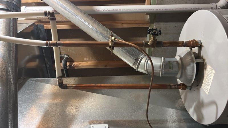 Conducted on-site assessment of residential water heater in basement utility area for replacement estimate. Unit evaluated is over 10 years old, showing visible signs of age including oxidation on copper supply lines and connections. Documented existing installation configuration including top-mounted copper piping with shut-off valves, pressure relief valve, expansion tank, and current venting system. Photographed unit specifications, mechanical room layout, and all plumbing connections to provide accurate replacement proposal for standard residential water heater installation.