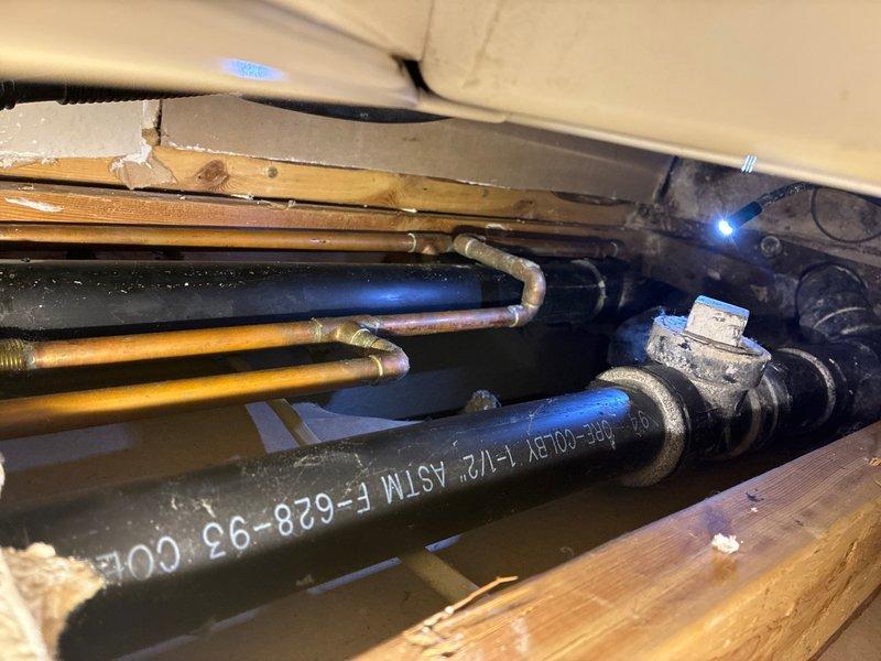 Conducted comprehensive assessment of failed 3" main drain stack serving multiple commercial kitchen sinks. The broken stack was located in the crawl space and exhibited active leaking at critical connection points. Documented existing piping infrastructure including copper supply lines, black ABS drainage piping with visible manufacturer specifications, and associated mechanical systems. Photographed compromised drain stack connections, structural joists, and surrounding plumbing components to provide detailed scope for replacement of the main drainage system serving all kitchen fixtures.