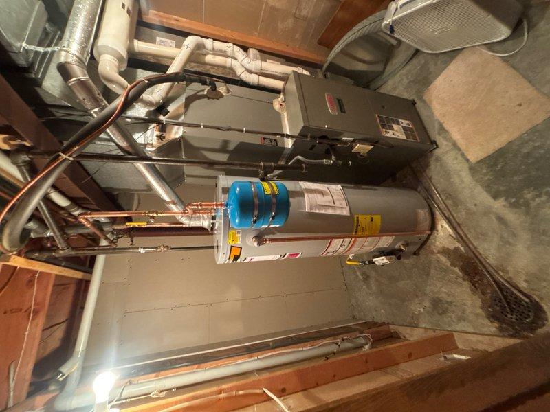 Completed installation of a STATE 40-gallon gas water heater in basement mechanical room. Installed thermal expansion tank per code requirements to protect against thermal expansion in closed plumbing systems. Connected all supply and discharge piping using copper pipe with proper shutoff valves, including blue-handled cold water inlet and red-handled hot water outlet for easy identification. Ensured proper venting configuration for gas appliance and verified all connections for leak-free operation. Unit positioned adjacent to existing HVAC equipment with adequate clearance for service access and code compliance.