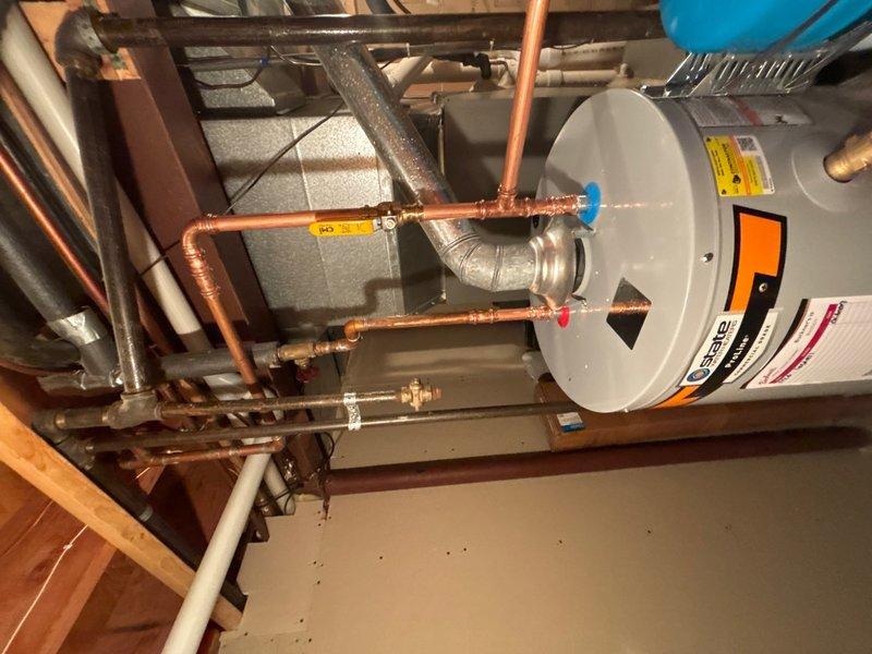 Completed installation of a STATE 40-gallon gas water heater in basement mechanical room. Installed thermal expansion tank per code requirements to protect against thermal expansion in closed plumbing systems. Connected all supply and discharge piping using copper pipe with proper shutoff valves, including blue-handled cold water inlet and red-handled hot water outlet for easy identification. Ensured proper venting configuration for gas appliance and verified all connections for leak-free operation. Unit positioned adjacent to existing HVAC equipment with adequate clearance for service access and code compliance.