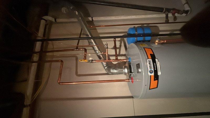 Installed a 50-gallon gas water heater with thermal expansion tank in collaboration with HVAC team. The unit was properly secured to the wall with safety strapping, and all copper piping connections were completed at the top of the heater for hot and cold water supply lines. Installation included protective insulation on water connections and proper clearances for maintenance access.