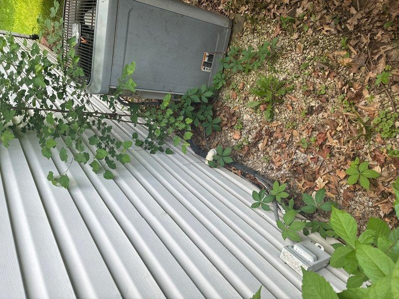 Completed comprehensive plumbing inspection of residential property. Documented aging plumbing infrastructure including deteriorated pipe insulation on main water line, oxidized brass valve assembly showing green patina, and mixed piping materials requiring monitoring. Also photographed exterior HVAC unit positioning and drainage considerations near building foundation.