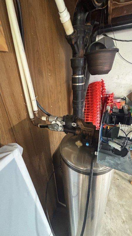 Replaced carbon filter on water softener system located in garage utility area. Serviced cylindrical stainless steel filtration tank with black control head assembly, ensuring proper installation and system functionality. Verified all connections, gauges, and pressure relief components operating correctly upon completion.