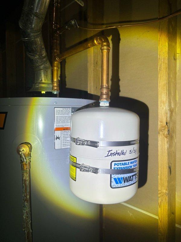 Completed preventive plumbing maintenance inspection on residential property. Inspected and photographed basement plumbing system including water heater, WATTS expansion tank (installed 5/2, over 10 years old), copper supply lines, and drainage components. Examined under-sink plumbing configuration including brass tailpiece, white P-trap with metal hose clamps, and braided stainless steel supply lines. All connections found intact and functional with age-appropriate discoloration on brass components but no active leaks detected.