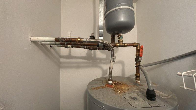 Reworked water heater piping connections and properly mounted thermal expansion tank to ensure code-compliant installation. The existing expansion tank was repositioned and securely mounted to structural support, with copper supply lines reconfigured for proper orientation and support. All connections were tested for leaks and system operation was verified upon completion.