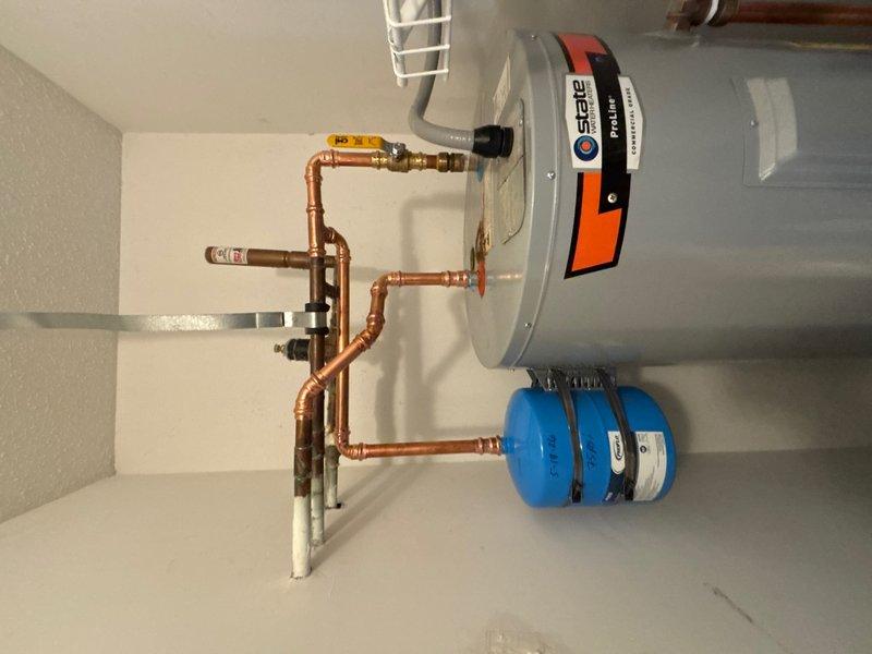 Reworked water heater piping connections and properly mounted thermal expansion tank to ensure code-compliant installation. The existing expansion tank was repositioned and securely mounted to structural support, with copper supply lines reconfigured for proper orientation and support. All connections were tested for leaks and system operation was verified upon completion.