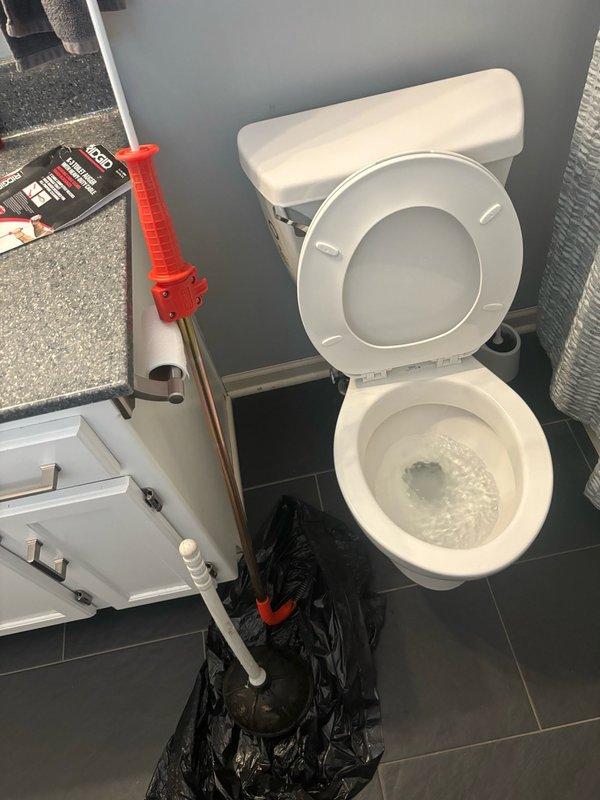 Responded to service call for slow-draining toilet in second-floor guest bathroom that was experiencing near-overflow conditions. Upon arrival, performed diagnostic assessment of toilet drainage system. Utilized plunger to clear blockage in toilet trap and drain line. Successfully restored proper flushing function and drainage flow. Tested toilet multiple times to verify complete resolution of slow drainage issue and confirmed no overflow conditions present. System operating normally upon completion.