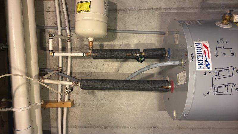Completed plumbing estimate for replacement of a 10-year-old tanked water heater located in basement. Assessed existing Freedom brand water heater system with expansion tank, copper supply lines, flexible braided connections, and PVC drain piping. Documented current installation including wall-mounted expansion tank with proper insulation, brass fittings, shutoff valves, and all plumbing connections to determine specifications and requirements for replacement unit.