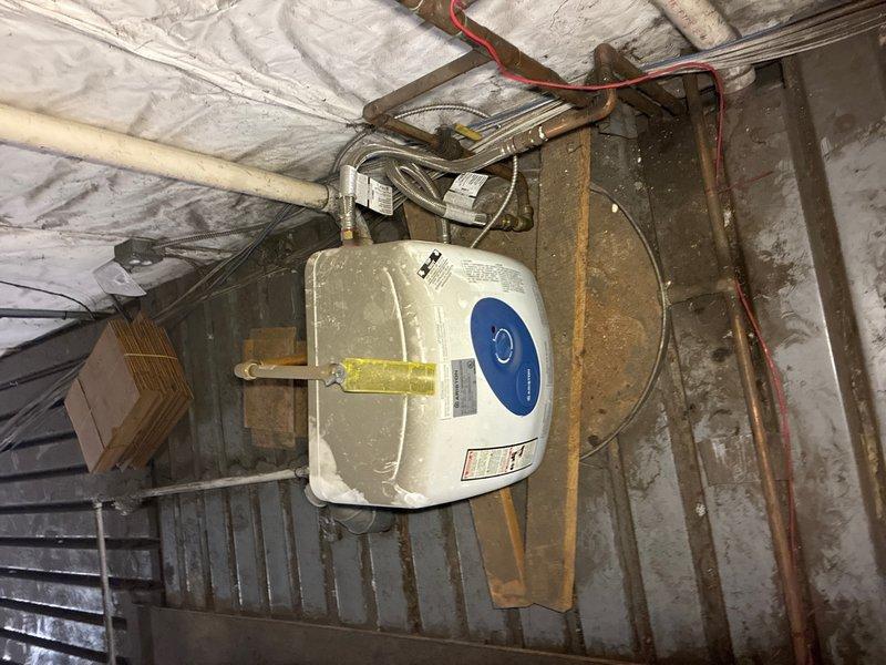 Conducted on-site evaluation for replacement of existing 6-gallon commercial water heater unit located in basement mechanical space. Assessed current installation including electrical connections, plumbing configurations, and mounting arrangement in spray foam insulated area. Documented existing equipment specifications, supply and discharge piping, electrical conduit routing, and structural support conditions. Photographed current water heater with visible manufacturer identification and surrounding utility infrastructure to provide accurate replacement estimate and ensure proper equipment sizing and installation planning.