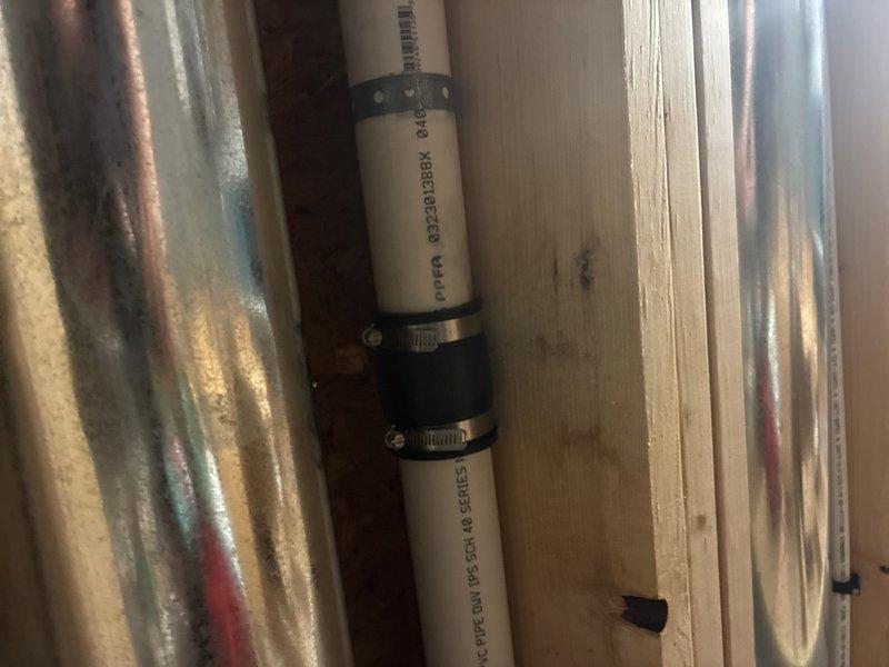 Responded to water leak in downstairs storage room caused by cracked drain pipe connected to upstairs laundry room. Identified compromised pipe section leaking wash water and detergent during washing machine discharge cycles. Removed damaged pipe segment and installed new section using rubber coupling with stainless steel hose clamps to create secure, watertight connection. Verified proper drainage flow and tested system through multiple wash cycles to confirm leak was eliminated. Documented repair with photos showing completed pipe repair within wall cavity framing.