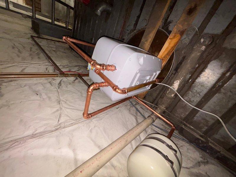 Installed a 6-gallon 120V Eemax electric water heater in commercial basement utility area with thermal expansion tank. Completed copper pipe connections with soldered joints and configured proper inlet/outlet plumbing to integrate unit into existing system. Installation includes proper electrical hookup and drain line routing to floor receptacle.