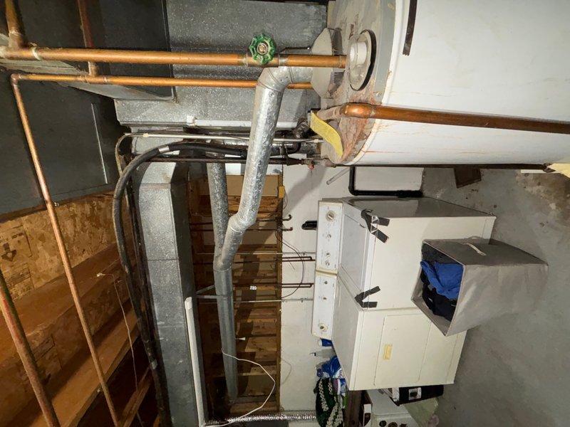 Conducted on-site evaluation of existing conventional tank-style water heater and basement utility infrastructure to provide tankless water heater replacement estimate. Assessed current plumbing configuration including copper supply lines, gas connections, venting requirements, and available clearances in utility area. Documented existing water heater location adjacent to laundry appliances and evaluated spatial constraints for tankless unit installation. Reviewed mechanical room layout including overhead pipe routing, electrical service accessibility, and proper ventilation pathways required for tankless system operation.