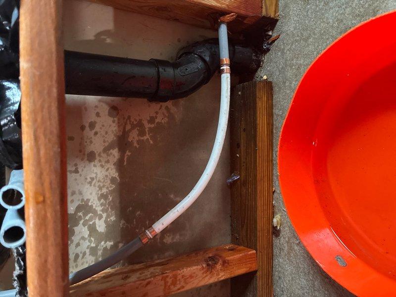 Responded to leak location request in basement area. Upon inspection, identified active leak in gray flexible hose connected to plumbing system beneath sink cabinet. Observed extensive water staining and discoloration on wooden cabinet surfaces and concrete floor, indicating prolonged water exposure from leaking hose. Documented conditions with photographs showing deteriorated cabinet interior, stained flooring, and compromised hose with visible wear at connection points. Advised customer of necessary hose replacement and potential cabinet remediation due to existing water damage.