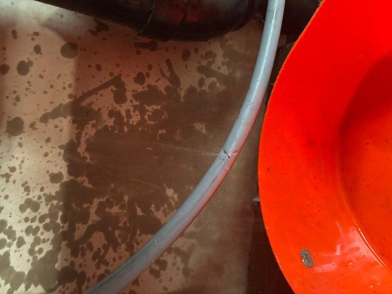 Responded to leak location request in basement area. Upon inspection, identified active leak in gray flexible hose connected to plumbing system beneath sink cabinet. Observed extensive water staining and discoloration on wooden cabinet surfaces and concrete floor, indicating prolonged water exposure from leaking hose. Documented conditions with photographs showing deteriorated cabinet interior, stained flooring, and compromised hose with visible wear at connection points. Advised customer of necessary hose replacement and potential cabinet remediation due to existing water damage.