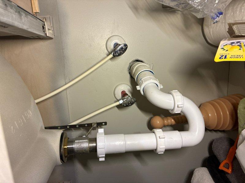 Completed plumbing maintenance visit involving inspection and documentation of under-sink drain assembly and bathroom fixtures. The P-trap configuration with white PVC piping, chrome basket strainers, and associated connections were photographed and verified for proper operation, with all bathroom plumbing fixtures confirmed to be in working order.
