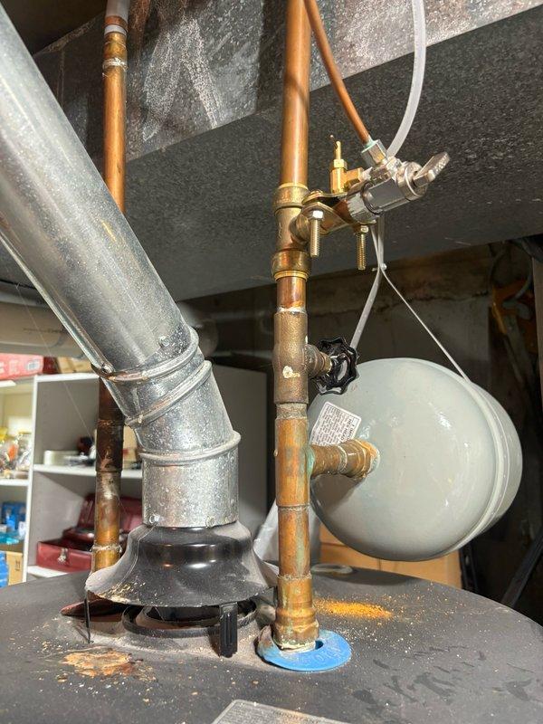 Responded to service call for 14-year-old tanked water heater with non-functioning pilot light in basement installation. Upon inspection, attempted to relight pilot assembly but unit failed to maintain flame. Given the age of the water heater and failed ignition system, recommended replacement due to end of serviceable life expectancy. Documented existing copper supply line connections, pressure relief valve assembly, and expansion tank configuration for future reference. Unit showed typical wear patterns consistent with age, including patina on copper fittings and connections.