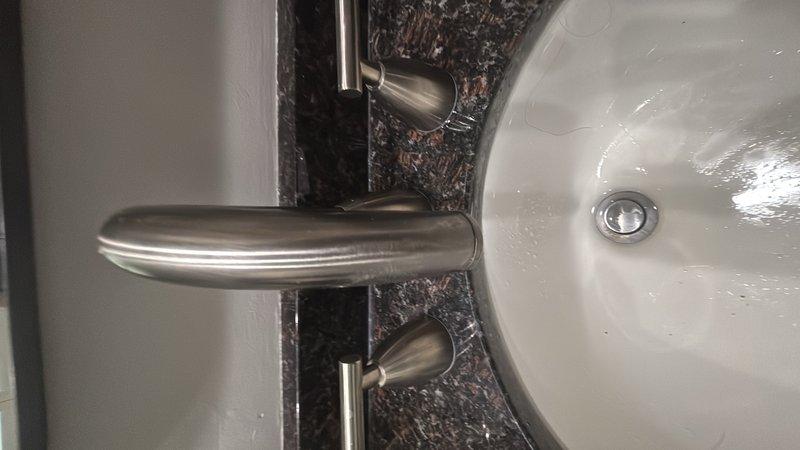 Responded to callback for water pressure issues at bathroom sink faucet where cartridge had been previously installed. Upon arrival, inspected the widespread bathroom faucet with brushed nickel finish mounted on granite countertop. Tested water flow from both hot and cold handles and evaluated cartridge operation. Verified proper installation and function of faucet components. Documented existing conditions with photos showing faucet assembly and sink basin from multiple angles for service records.
