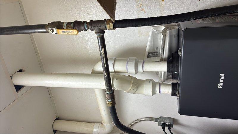 Completed warranty replacement of two Rinnai tankless water heater units in commercial facility. Removed existing failed units and installed new Rinnai tankless water heaters with proper venting using white PVC piping, connected gas supply lines with flexible black conduit and brass fittings, and integrated copper water supply piping with shut-off valves. All connections were tested and verified operational upon completion.