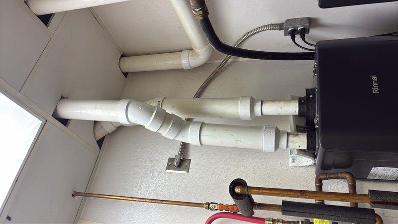 Completed warranty replacement of two Rinnai tankless water heater units in commercial facility. Removed existing failed units and installed new Rinnai tankless water heaters with proper venting using white PVC piping, connected gas supply lines with flexible black conduit and brass fittings, and integrated copper water supply piping with shut-off valves. All connections were tested and verified operational upon completion.