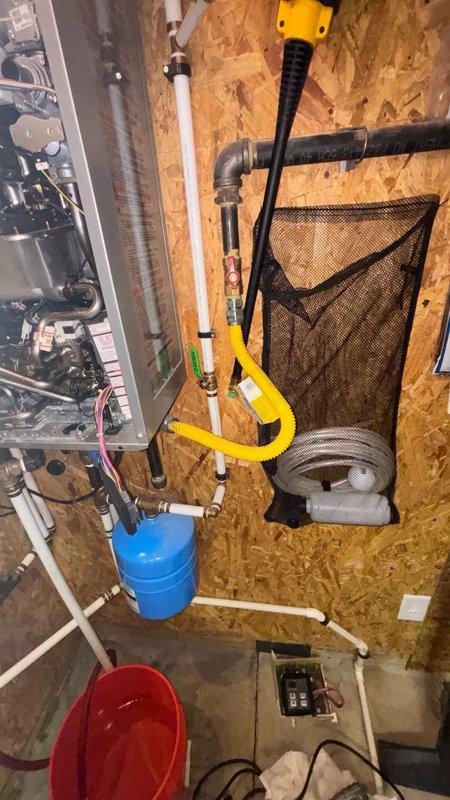 Completed installation of control board, control panel, and temperature/pressure relief pipe on tankless water heater system. Replaced failed control board with new unit, secured all electrical connections including multi-colored wiring harnesses, and installed proper relief piping with code-compliant discharge termination. Verified all brass valves, pressure gauges, and safety devices are functioning correctly, tested system operation, and confirmed unit is heating properly with no error codes displayed.