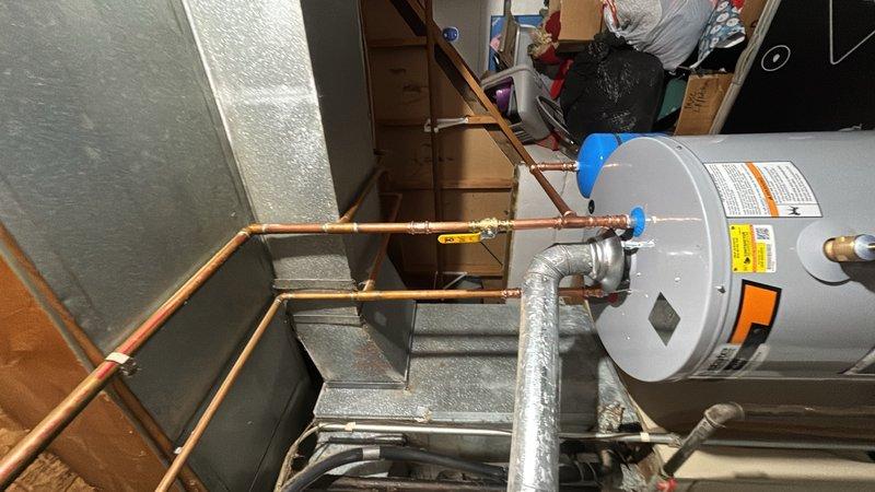 Installed a new 50-gallon gas water heater in the basement utility area, connecting copper supply lines with shut-off valves and proper insulation. The unit was positioned on a stable platform with gas line connection featuring a yellow shut-off valve for safety compliance. All plumbing connections were secured and tested to ensure proper operation of the residential water heating system.