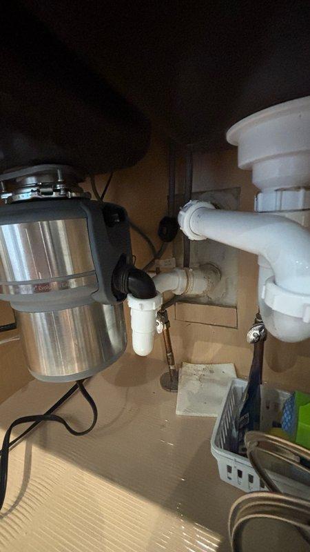 Responded to service call for locked-up In-Sinkerator garbage disposal unit under kitchen sink. Upon inspection, identified jamming issue potentially caused by foreign object (small "S" hook) that may have fallen into disposal chamber. Accessed disposal unit from cabinet beneath sink, cleared obstruction, and tested unit operation to ensure proper functionality. Verified all plumbing connections, P-trap configuration, and electrical connections were secure and operating correctly. Disposal unit restored to normal working condition with no leaks detected.