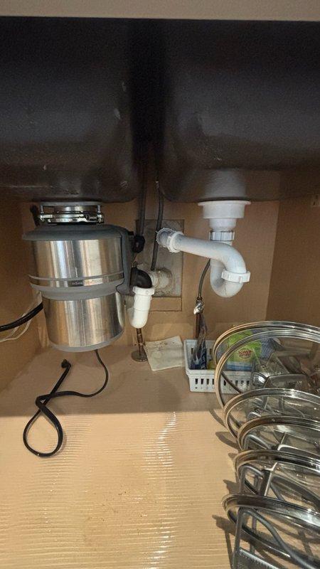 Responded to service call for locked-up In-Sinkerator garbage disposal unit under kitchen sink. Upon inspection, identified jamming issue potentially caused by foreign object (small "S" hook) that may have fallen into disposal chamber. Accessed disposal unit from cabinet beneath sink, cleared obstruction, and tested unit operation to ensure proper functionality. Verified all plumbing connections, P-trap configuration, and electrical connections were secure and operating correctly. Disposal unit restored to normal working condition with no leaks detected.
