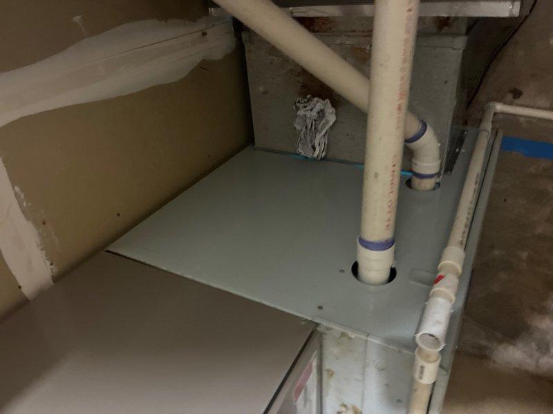 Conducted on-site assessment of commercial building's main sewer drain line to provide estimate for repair or replacement due to identified belly in the line. Inspected interior plumbing cabinet containing vertical PVC drainage system with blue rubber couplings, and evaluated mechanical room housing furnace, water heater, and associated drainage infrastructure including horizontal blue PVC pipe and vertical white PVC drain with floor connection. Documented existing plumbing configuration and conditions to prepare comprehensive bid as part of three-estimate requirement for building's board of directors.
