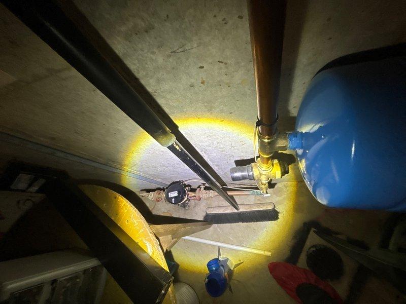 Completed plumbing maintenance inspection of water heater and pressure tank system. Inspected all copper piping connections, brass fittings, pressure relief valve configuration, and pressure gauge at T-fitting junction, confirming proper installation and operation of both the water heater unit and blue pressure tank with associated plumbing components.