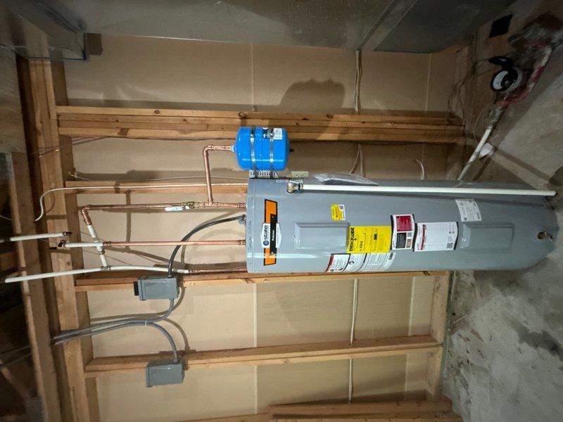 Completed installation of a 50-gallon electric water heater with thermal expansion tank and ball valve shut-off in basement utility area. Installed secondary electrical disconnect box with proper conduit routing to provide code-compliant power shutoff for the water heater circuit. All copper supply lines, electrical connections, and safety components were properly secured and tested for operation.