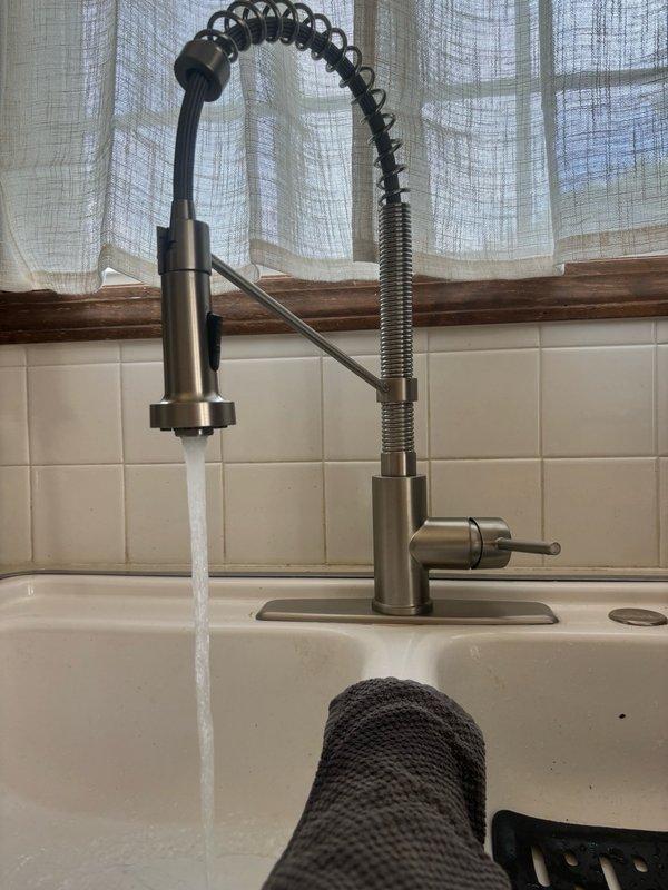 Responded to no hot water issue at kitchen sink faucet in 27-year-old home. Diagnosed faulty hot water supply line connection under sink affecting only the kitchen fixture while rest of house maintained proper hot water flow. Accessed plumbing connections beneath sink, identified and corrected the supply line issue to the 10-year-old pull-down style kitchen faucet with spring coil neck and single lever handle. Verified proper hot and cold water flow upon completion, with faucet now operating correctly at normal temperature and pressure.