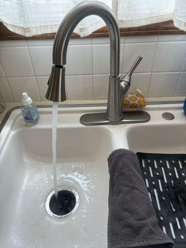 Responded to no hot water issue at kitchen sink faucet in 27-year-old home. Diagnosed faulty hot water supply line connection under sink affecting only the kitchen fixture while rest of house maintained proper hot water flow. Accessed plumbing connections beneath sink, identified and corrected the supply line issue to the 10-year-old pull-down style kitchen faucet with spring coil neck and single lever handle. Verified proper hot and cold water flow upon completion, with faucet now operating correctly at normal temperature and pressure.