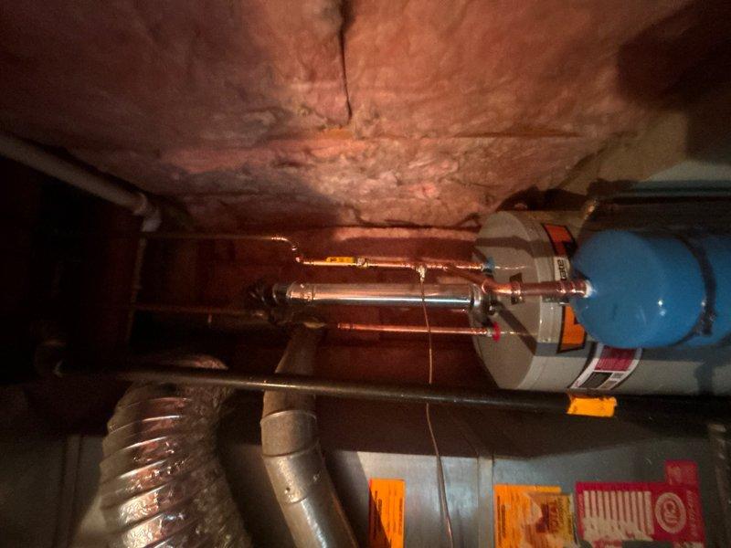 Completed installation of a 50-gallon gas-fired water heater in basement utility area. Removed existing unit and installed new tank with proper venting connections to existing HVAC ductwork. Installed thermal expansion tank with blue dome top, connected via copper piping to main water heater supply lines. All copper connections were soldered and pressure-tested to ensure leak-free operation. Unit was positioned on stable platform, with gas line and water supply connections completed per manufacturer specifications and local plumbing code requirements. System was tested for proper operation, including pilot light ignition, burner function, and temperature settings.