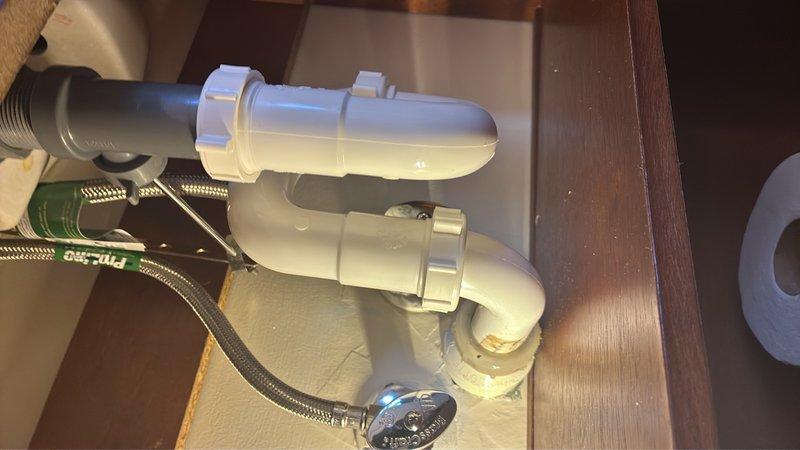 Responded to a water leak issue in a half bath where the P-trap under the sink was actively leaking. Upon inspection, found the existing P-trap assembly had failed connections causing water discharge. Removed and replaced the defective P-trap with new white PVC components, ensuring proper alignment and secure compression fittings. Also inspected the dishwasher discharge line and kitchen sink trap assembly as requested, verifying proper drainage and connection integrity. All plumbing fixtures were tested for leaks and confirmed operational. Removed old corroded brass and copper fittings from the failed assembly. System is now functioning properly with no active leaks detected.