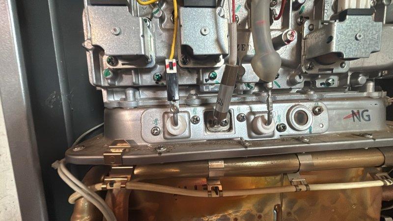 Replaced defective sparker and flame rod assembly on heating system, including installation of new flame rod gasket. The original components showed significant deterioration and material degradation, which was compromising ignition reliability. Removed failed ignition assembly, cleaned mounting surfaces, and installed new sparker, flame rod, and gasket to restore proper burner ignition and flame sensing capability.