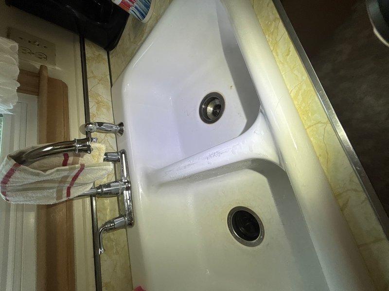 Responded to kitchen water leak complaint with water appearing on floor during washer operation and slow drainage on garbage disposal. Upon inspection, identified water damage to cabinet floor beneath sink with significant staining and deterioration of wooden surfaces. Examined P-trap assembly, water supply lines, and drainage connections for source of leak. Investigated plumbing connections associated with washing machine discharge and garbage disposal drain line. Documented existing water damage and compromised cabinet materials resulting from moisture exposure. Addressed drainage issue affecting garbage disposal operation and traced potential leak sources in under-sink plumbing system.