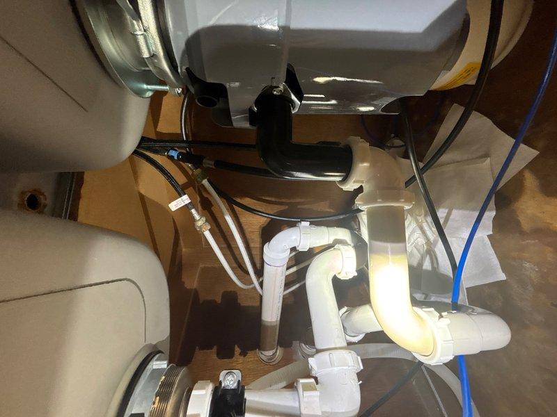 Successfully installed new kitchen faucet with modern curved spout design over dual-basin stainless steel sink. Verified proper water supply connections, tested flow and drainage through existing P-trap plumbing assembly, and confirmed no leaks at all connection points.
