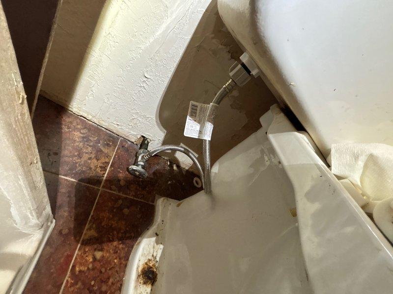 Responded to reported toilet leak in basement bathroom. Upon inspection, found extensive water staining on ceramic tile flooring surrounding toilet base, indicating chronic leakage. Inspected toilet tank interior and identified deteriorated flush valve flapper as primary source of leak. Tank showed significant mineral deposits and rust staining on interior surfaces, confirming prolonged water seepage. Replaced worn red rubber flapper assembly and inspected water supply line connection for integrity. Tested flush mechanism multiple times to ensure proper seal and verified no active leaking from tank or base connection. Documented pre-repair conditions showing floor discoloration and tank component deterioration.