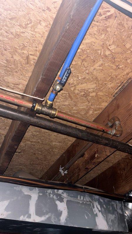 Responded to complaint of loud, intermittent bumping noises in water pipes occurring throughout the day, even when water was not in use. Inspected plumbing system in basement/crawl space of 1970s-era home where previous service call had not identified the cause. Diagnosed water hammer condition caused by inadequate air chambers and possible loose pipe mounting. Examined exposed copper and black piping runs, checked shut-off valves and mounting brackets for proper securing. Installed water hammer arrestor at strategic location to absorb hydraulic shock and prevent pressure spikes in the system. Secured loose pipe hangers and added additional support brackets where needed to minimize pipe movement and vibration transmission through structural framing.
