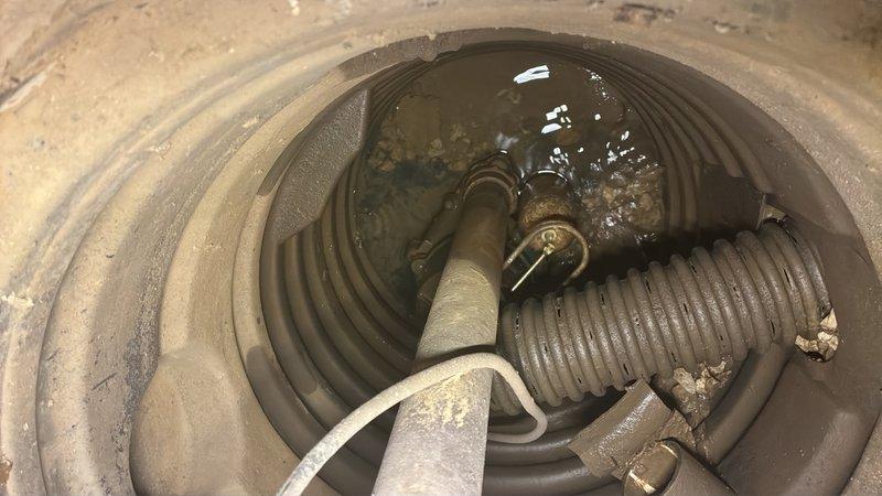 Responded to basement flooding issue following recent rainfall. Upon inspection, found existing sump pump basin with standing water and visible sediment accumulation. Assessed pump functionality, discharge line connections, and basin condition. Corrugated flex hose and piping connections showed signs of age with dust buildup present throughout the system.