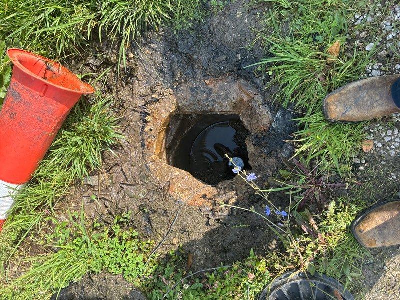 Responded to water leak emergency at meter pit location. Upon arrival, found meter pit completely flooded with standing water obscuring the water meter and service connections. Deployed pump equipment to extract accumulated water from the pit to allow proper inspection and assessment of the leak source. Excavated and exposed the water service line area beneath the meter for visual examination of pipe connections, meter coupling, and surrounding infrastructure. Documented existing conditions through photography showing flooded pit with measurement tools deployed, utility access points, and work area setup with safety equipment in place. Completed initial assessment to determine leak origin and extent of damage to water service components.