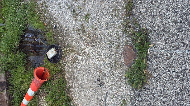 Responded to water leak emergency at meter pit location. Upon arrival, found meter pit completely flooded with standing water obscuring the water meter and service connections. Deployed pump equipment to extract accumulated water from the pit to allow proper inspection and assessment of the leak source. Excavated and exposed the water service line area beneath the meter for visual examination of pipe connections, meter coupling, and surrounding infrastructure. Documented existing conditions through photography showing flooded pit with measurement tools deployed, utility access points, and work area setup with safety equipment in place. Completed initial assessment to determine leak origin and extent of damage to water service components.