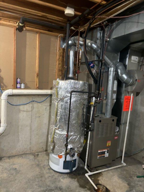 Responded to emergency service call for leaking 10+ year old 50-gallon gas water heater in basement utility room. Upon inspection, confirmed active leak originating from bottom of tank, indicating internal tank failure requiring immediate replacement. Assessed existing installation including gas supply line with shutoff valve, copper water supply piping, temperature/pressure relief valve, and venting configuration adjacent to furnace system. Documented current equipment condition and surrounding mechanical room layout. Provided estimate for replacement with new 50-gallon gas water heater to be installed within 24-48 hours to restore hot water service.