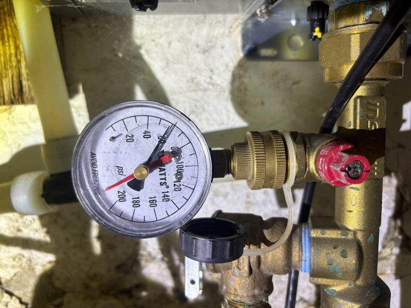 Completed scheduled plumbing maintenance visit including tankless water heater flush and water softener service. Inspected and serviced pressure regulation system with gauge reading within normal operating parameters, verified all brass valve connections and fittings for proper operation, and confirmed system pressures were properly maintained throughout the equipment.