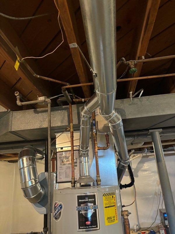 Completed water heater replacement in basement utility area. Removed existing unit and installed new Bradford White BRUTE model water heater with proper venting through existing ductwork system. Connected copper water supply lines, installed blue shutoff valve for system isolation, and verified all plumbing connections for proper operation and code compliance. Unit secured and tested successfully.