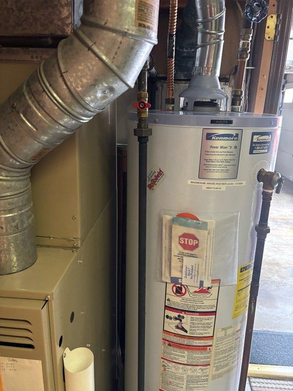 Responded to no hot water complaint for residential water heater over 10 years old located in basement. Upon arrival, inspected Kenmore water heater unit and associated plumbing connections, including pressure gauge and supply lines. Documented existing equipment condition and configuration with photographs showing water heater, furnace, and pressure monitoring equipment. Provided estimate for water heater replacement based on age of unit and lack of hot water production.