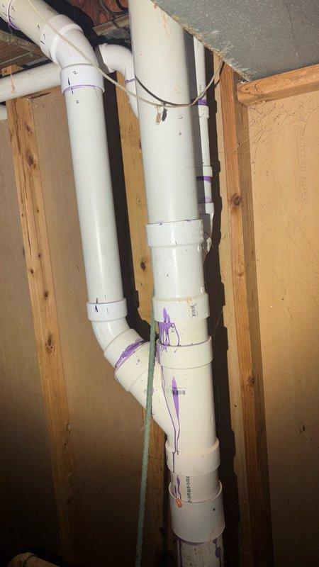 Responded to a backed up main drain in the basement. Upon arrival, found significant sewage backup with black residue covering the utility room floor. Cleared the main drain line obstruction and restored proper drainage flow. Inspected the vertical PVC drain and waste piping system running through the wall cavity to verify proper function and ensure no additional blockages in the secondary lines. Cleanup of affected area completed following successful drain clearing.