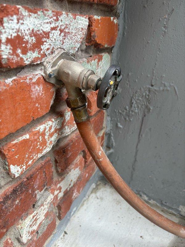 Completed scheduled plumbing maintenance inspection of exterior hose bib and water heater supply connections. Exterior spigot on brick wall showed normal operation with significant efflorescence present on surrounding masonry indicating historical moisture exposure. Inspected water heater flexible supply lines and verified proper installation and connection integrity of braided stainless steel flex lines with no visible leaks or deterioration noted.