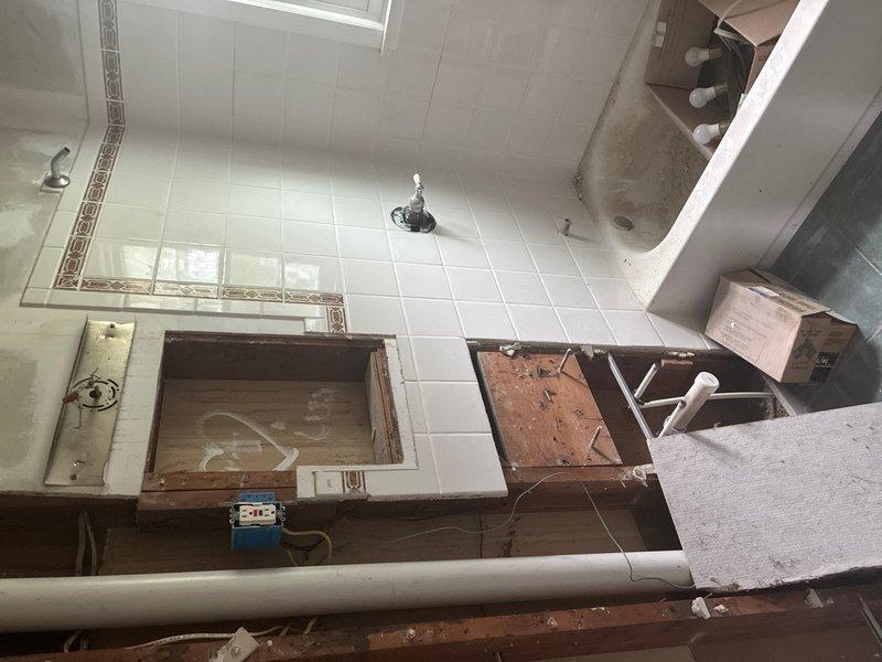 Provided comprehensive plumbing estimate for property requiring new water heater installation, first-floor toilet replacement, second-floor toilet reset, and first-floor vanity installation. Property currently has no existing water heater system. Assessed bathroom conditions showing ongoing renovation work with exposed wall access panels, existing bathtub with plumbing fixtures, and under-sink drainage assembly with PVC trap configuration. Documented all areas requiring plumbing installations and modifications to support new fixture placements.